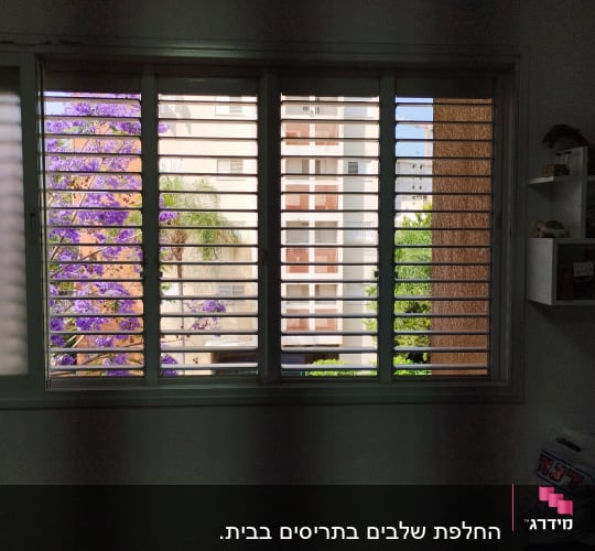 תריסים אופקיים על חלון עם נוף חיצוני